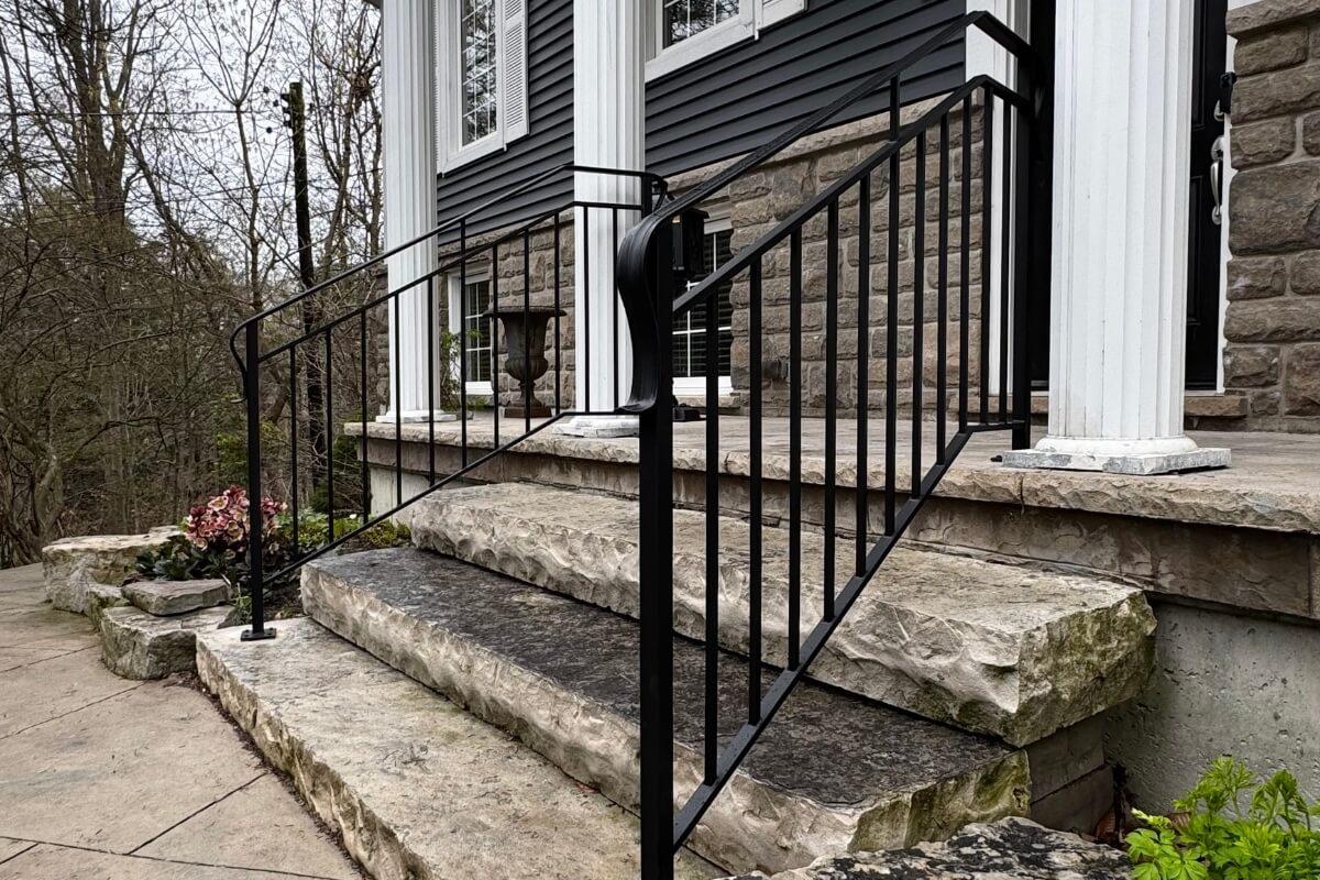 Custom black exterior steel railings with curved top handrail on natural stone entrance steps